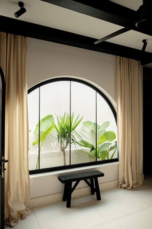 Ein Zimmer mit einem großen Rundbogenfenster, einer Bank und Vorhängen.