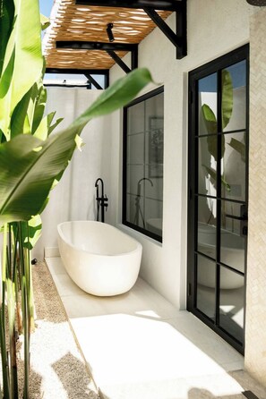 Ein modernes Badezimmer mit freistehender Badewanne, großen Fenstern und einer Pergola.