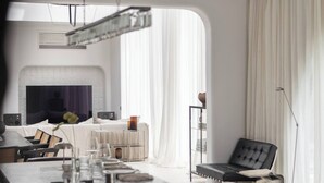 Cozinha moderna com ilha de mármore, lareira e sala de jantar com uma cadeira de couro preta.