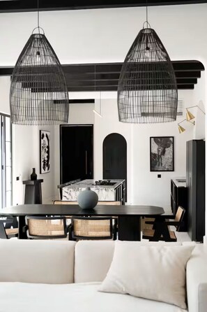 A modern dining area with a round table, wicker chairs, and black hanging pendant lights. - Gorgeous 2 Br , 100m from beach (Seseh)