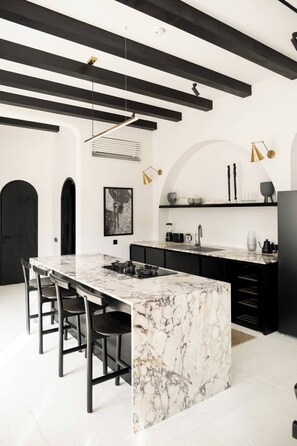 A modern kitchen with a marble island, black cabinetry, and pendant lighting. - Gorgeous 2 Br , 100m from beach (Seseh)