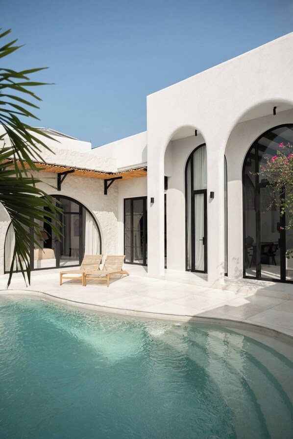 A modern building with a pool, arched windows, and a covered patio area. - Gorgeous 2 Br , 100m from beach (Seseh)