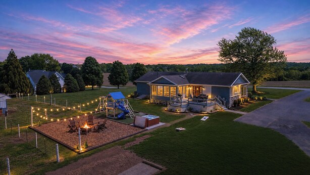 Ein Haus mit Terrasse, Spielbereich und Feuerstelle.