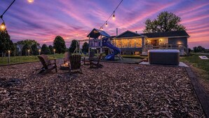 Ein Spielplatz mit Rutschen und Schaukeln, ein Whirlpool und ein Haus mit Veranda.