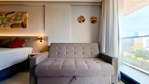 Ein Hotelzimmer mit einem Bett, einem Sofa, einer Wandleuchte und zwei Wanddekorationen.