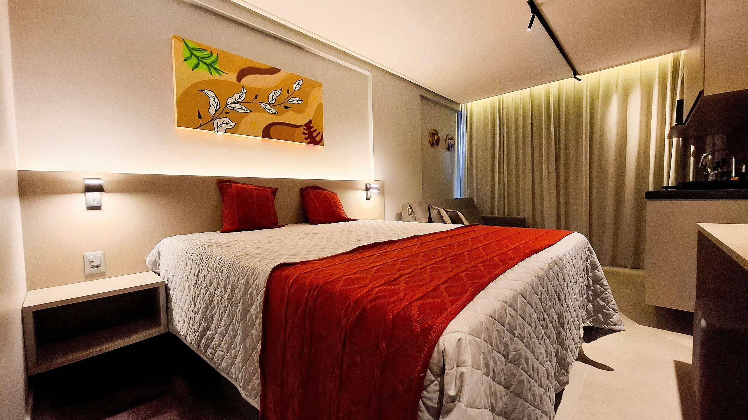 Ein modernes Hotelzimmer mit einem großen Bett, einem Nachttisch, einem Schreibtisch und einem Bild an der Wand.