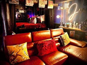 Eine Bar mit einer Ledersofa, hängenden Dekorationen und einem Neonzeichen.