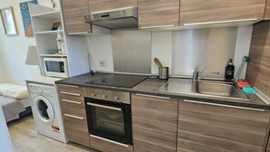 A compact kitchen with a microwave, oven, sink, and wooden cabinets.