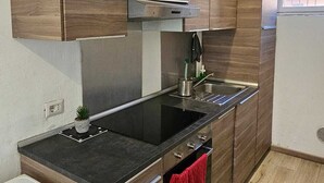 A modern kitchen with wooden cabinets, a black countertop, a stainless steel sink, and a built-in oven.