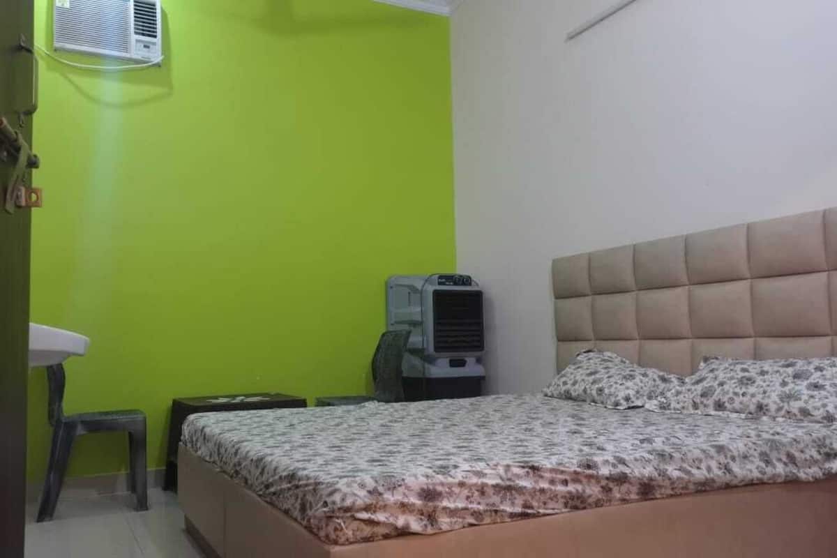 A bedroom with a bed, a bedside table, a chair, a radiator, and a wall-mounted air conditioner.
