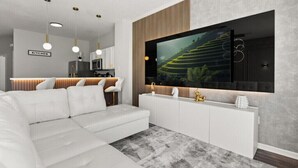 Ein modernes Wohnzimmer mit einem Ecksofa, einem flachbildfernseher an der Wand, einer Küche im Hintergrund und einem großen Fenster.
