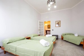 Ein Hotelzimmer mit zwei Einzelbetten, einem Schrank, einem Schreibtisch und einem Stuhl.