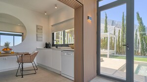 Eine moderne Küche mit Essbereich, Geschirrspüler und großem Fenster mit Blick auf einen Pool.