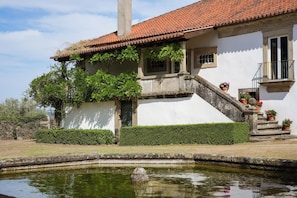 A building with a tiled roof, a stone staircase, and a small garden with a pond. - Feel Discovery Casa Vilarinho São Romão (Sabrosa)