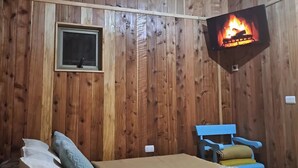 A wooden room with a bed, a TV mounted on the wall, and a window. - Cabins in Pucon (Araucanía)