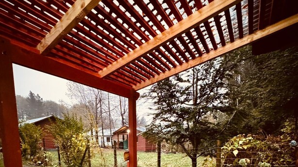 A covered outdoor seating area with a pergola, a table, and two chairs. - Cabins in Pucon (Araucanía)