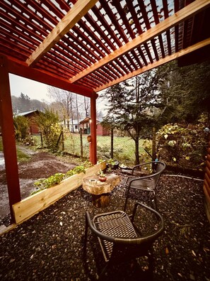 Et overdækket udendørs område med en pergola, et bord og to stole.