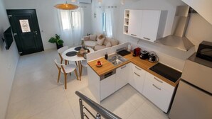A modern kitchen with white cabinets, a wooden countertop, and a built-in stove.