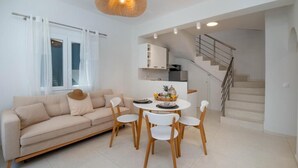 A modern living room with a sofa, dining table, chairs, and a staircase.