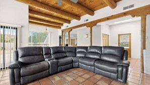 A sectional sofa in a room with wooden beams, tiled flooring, and large windows. - Private Pool + Mountain Views -Retreat Near ABQ (Placitas)