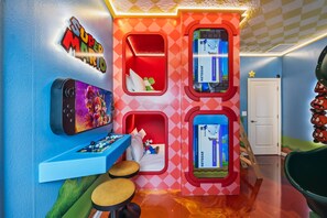 Une pièce dont un des murs est décoré sur le thème de Nintendo, avec une console Nintendo Switch et un écran pour Nintendo Switch.