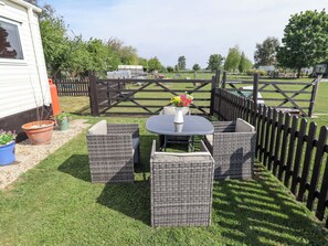 A patio with wicker furniture, a table, and a vase of flowers.