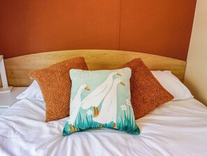 A bed with white bedding, two brown pillows, and a pillow with a white duck design. - Ewe View (Boston)