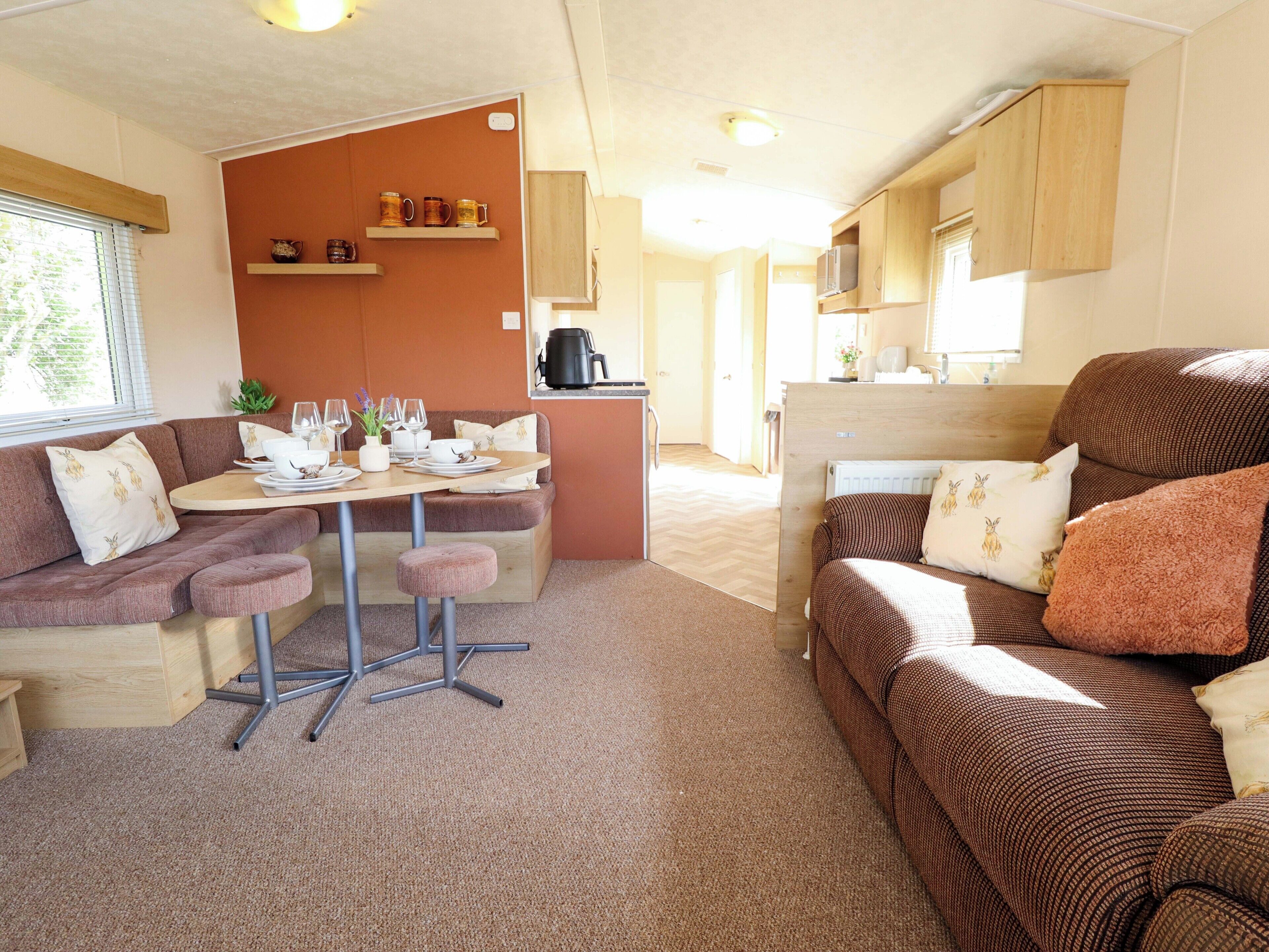 Interior de una caravana compacta con zona de comedor, kitchenette y asientos.