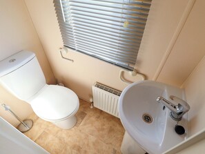 A small bathroom with a toilet, a sink, a window with blinds, and a radiator. - Ewe View (Boston)