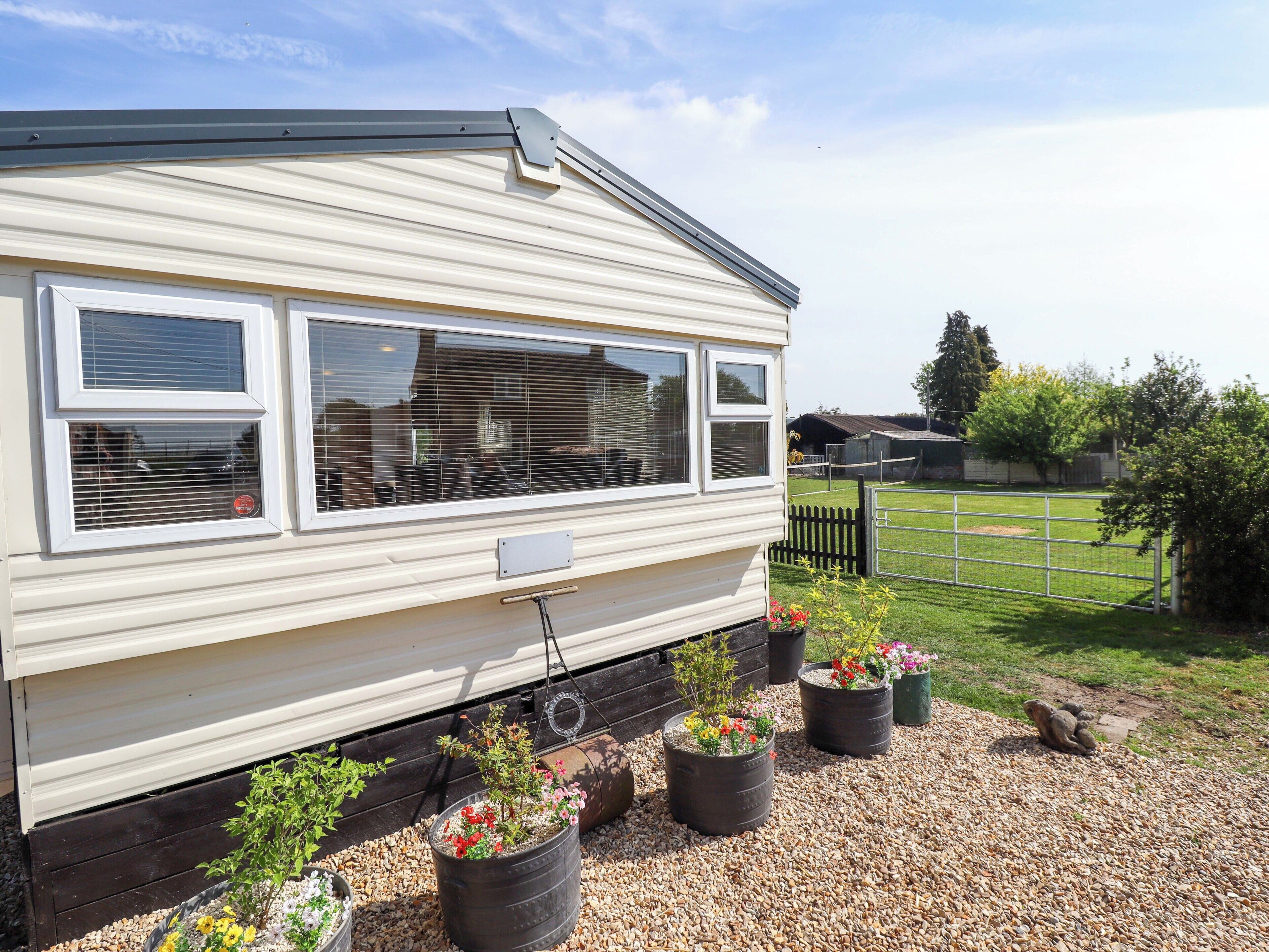 A mobile home with a large window, a small porch area, and potted plants.