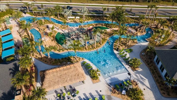Luchtbeeld van een resort met een kronkelend zwembad, loungegedeeltes en palmbomen.