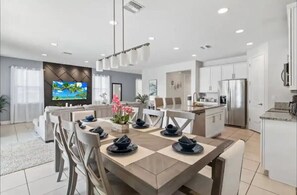 A modern kitchen with a central island, white cabinetry, and a stainless steel refrigerator. - Last Minute Disney Getaway! Private Pool, Game Room & Themed Bedrooms. Book Now! #170009 (Orlando)