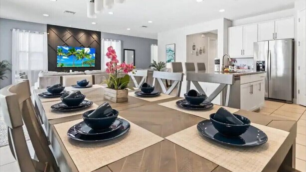 Eine moderne Küche mit weißen Schränken, einem Edelstahlkühlschrank und einem Essbereich mit Tisch für sechs Personen.