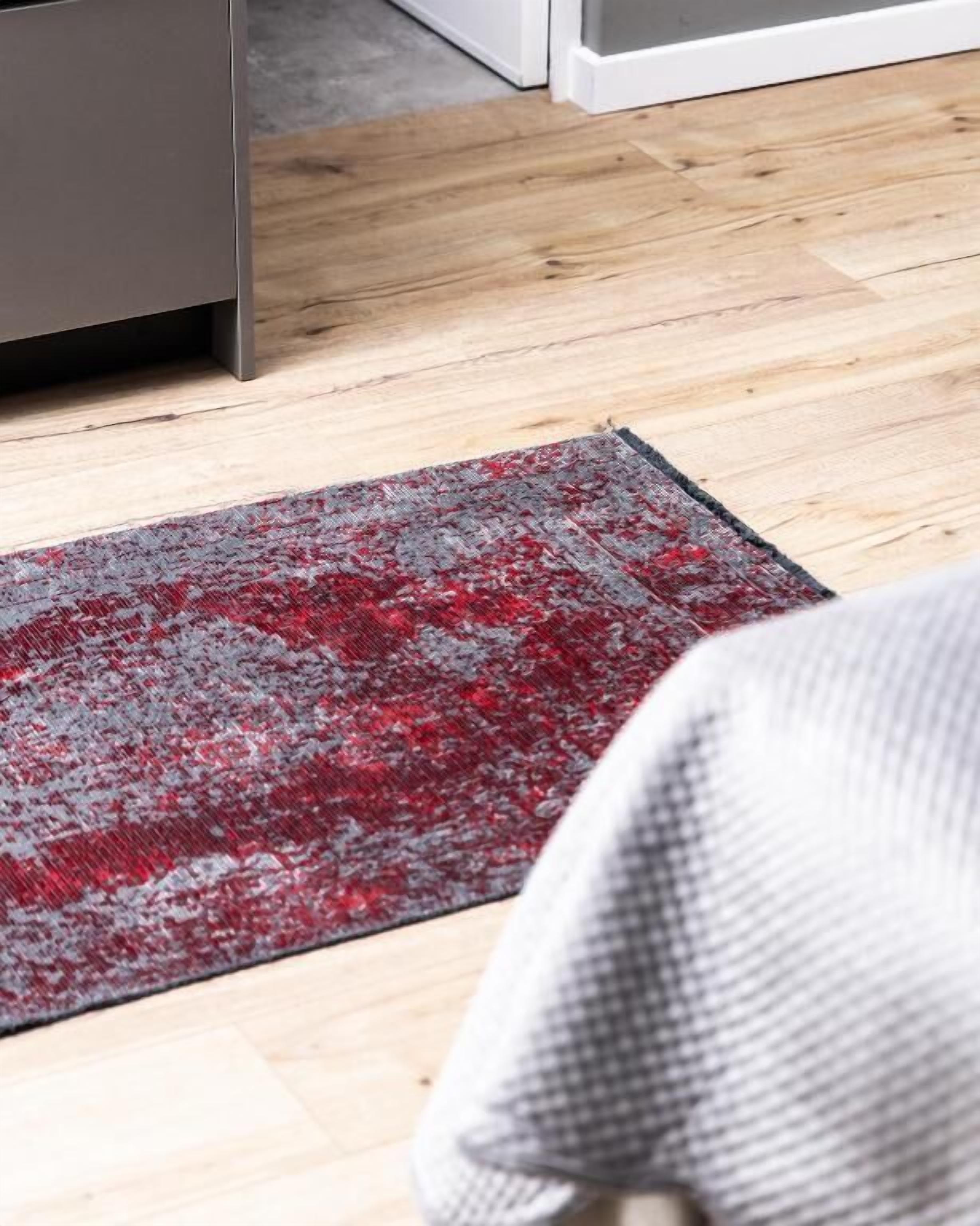 Een houten vloer met een rood en grijs vloerkleed.