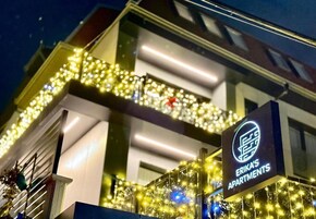 Un edificio con un cartel que dice Erika's Apartments, con un balcón adornado con luces de cadena.