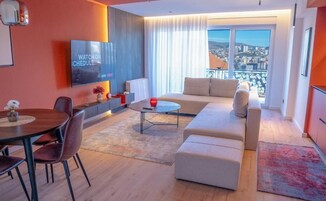 Una sala de estar moderna con un sofá, una mesa de comedor y un televisor montado en la pared.