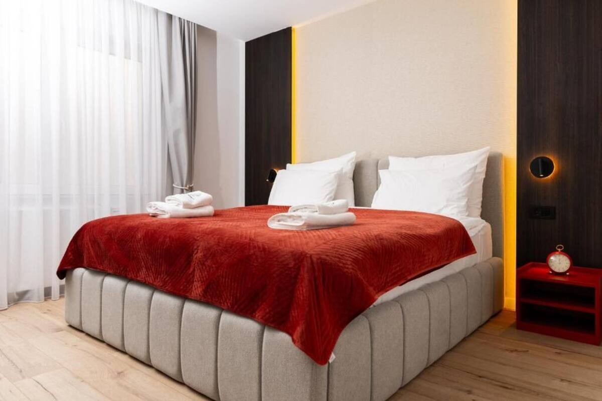 Moderni hotellihuone, jossa on suuri sänky, yöpöytä ja yövalaisin.