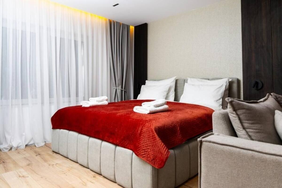 Hotellihuone, jossa on sänky, sohva ja verho.