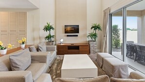 A spacious living area with a sofa set, a coffee table, a TV mounted on the wall, and potted plants. - Last Minute Disney Getaway! Modern Townhome with Private Balcony. Book Now! #170017 (Orlando)