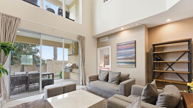 A spacious living area with a sofa set, a coffee table, and a bookshelf. - Last Minute Disney Getaway! Modern Townhome with Private Balcony. Book Now! #170017 (Orlando)