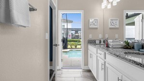 A modern kitchen with a view of a swimming pool, white cabinets, granite countertops, and a door leading outside. - Last Minute Disney Getaway! Private Pool & Themed Bedrooms. Book Now! #166559 (Orlando)