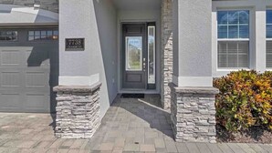 Une maison avec une façade en pierre, un garage et une porte d’entrée portant un numéro.