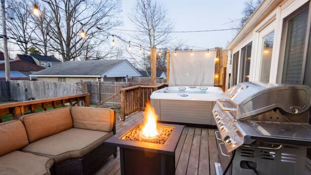 Een terras buiten met een vuurkorf, een barbecue en een jacuzzi.