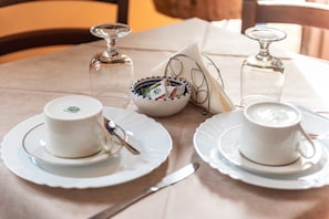 A table set with white cups, saucers, a bowl with utensils, and two glass bottles. - Room 'B&B San Domenico - Superior Quadruple' with Balcony, Wi-Fi and Air Conditioning (Realmonte)