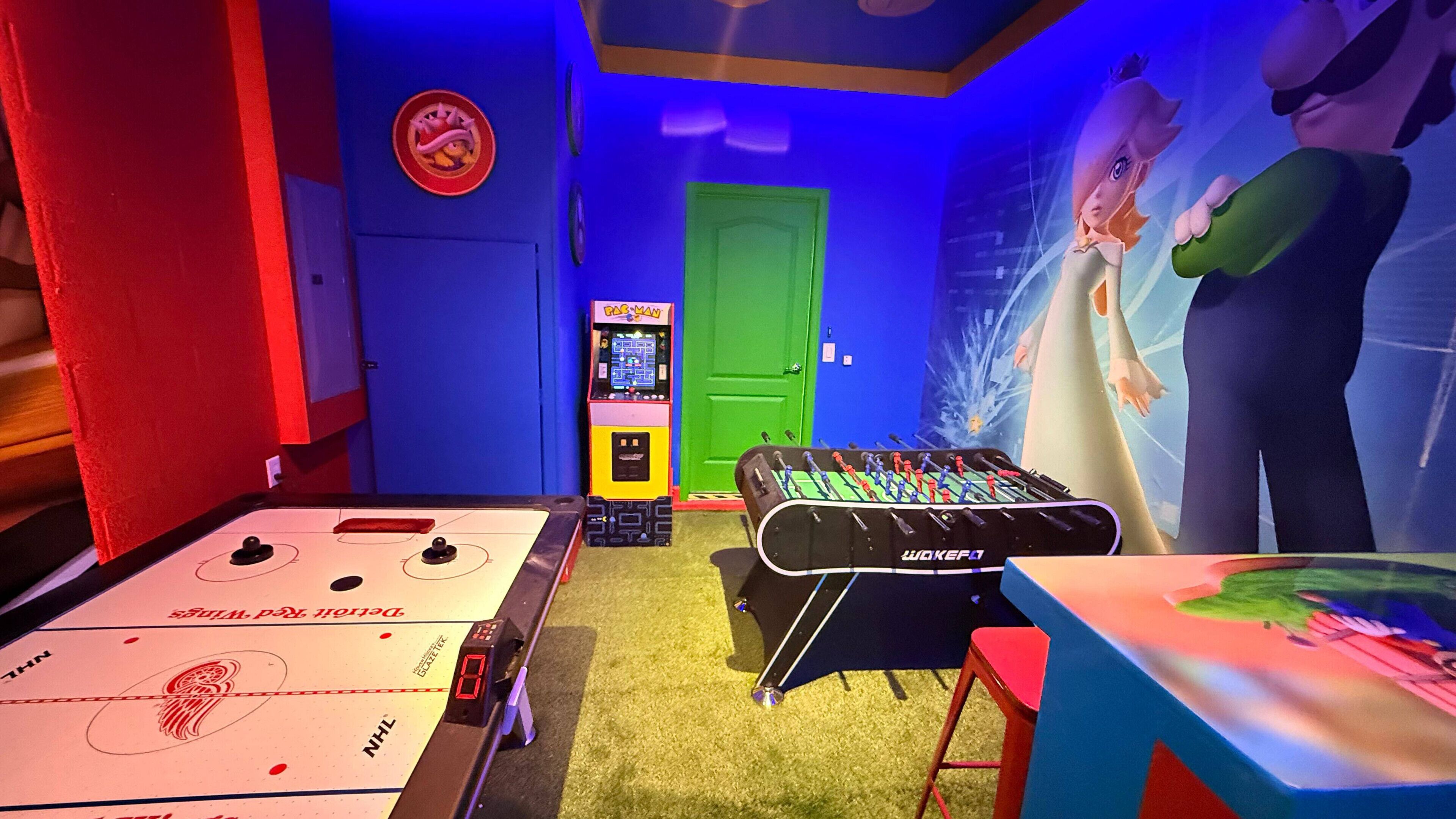 Une pièce équipée d’un baby-foot, d’une table de ping-pong et d’une console de jeux vidéo.