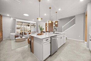 A modern kitchen with a central island, pendant lighting, and a staircase leading to a loft area. - Last Minute Disney Getaway! Private Pool & Themed Bedrooms. Book Now! #167327 (Orlando)