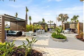 An outdoor patio area with seating arrangements, covered sections, and palm trees. - Last Minute Disney Getaway! Private Pool & Themed Bedrooms. Book Now! #167327 (Orlando)