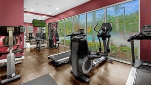 A gym with cardio machines, weightlifting equipment, and large windows offering a view of greenery. - Last Minute Disney Getaway! Modern & Comfortable Bedrooms. Book Now! #166509 (Orlando)