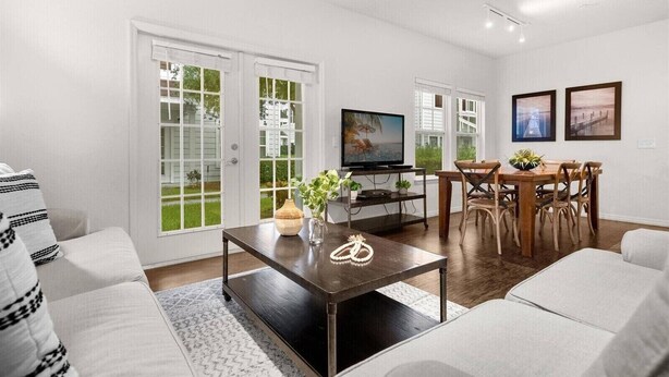 A living room with a TV, dining table, and chairs, a sofa, and a coffee table with decorative items. - Last Minute Disney Getaway! Modern & Comfortable Bedrooms. Book Now! #166509 (Orlando)