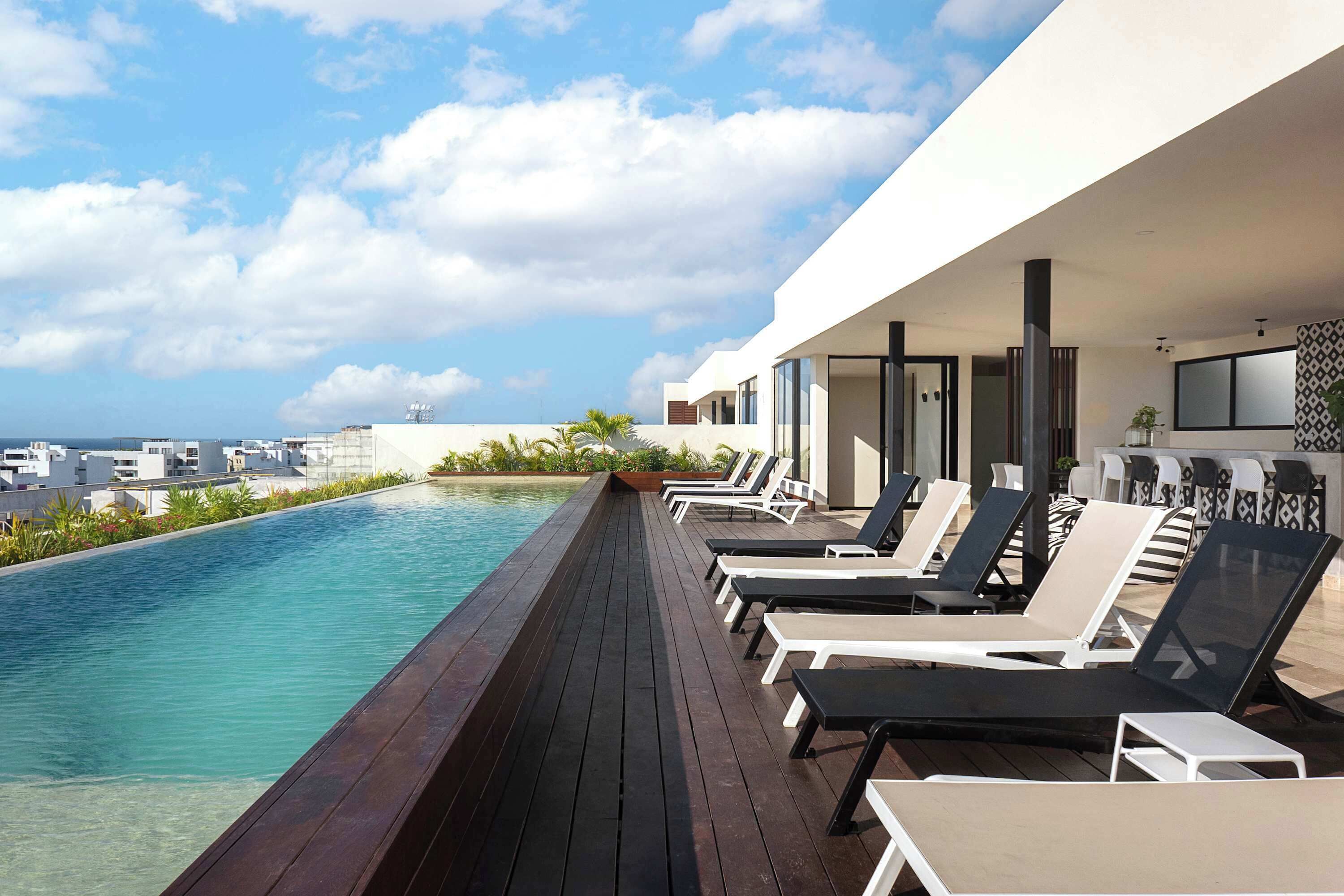 A rooftop pool with lounge chairs and a view of the city skyline.